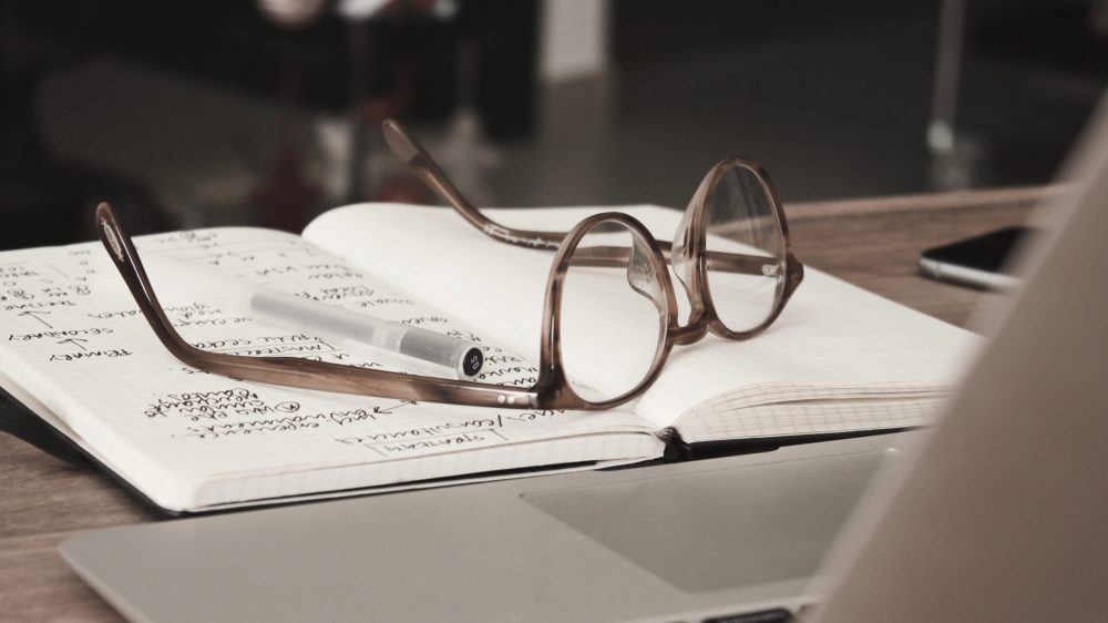 Present Tense in Spanish — a pair of glasses on an open notebook