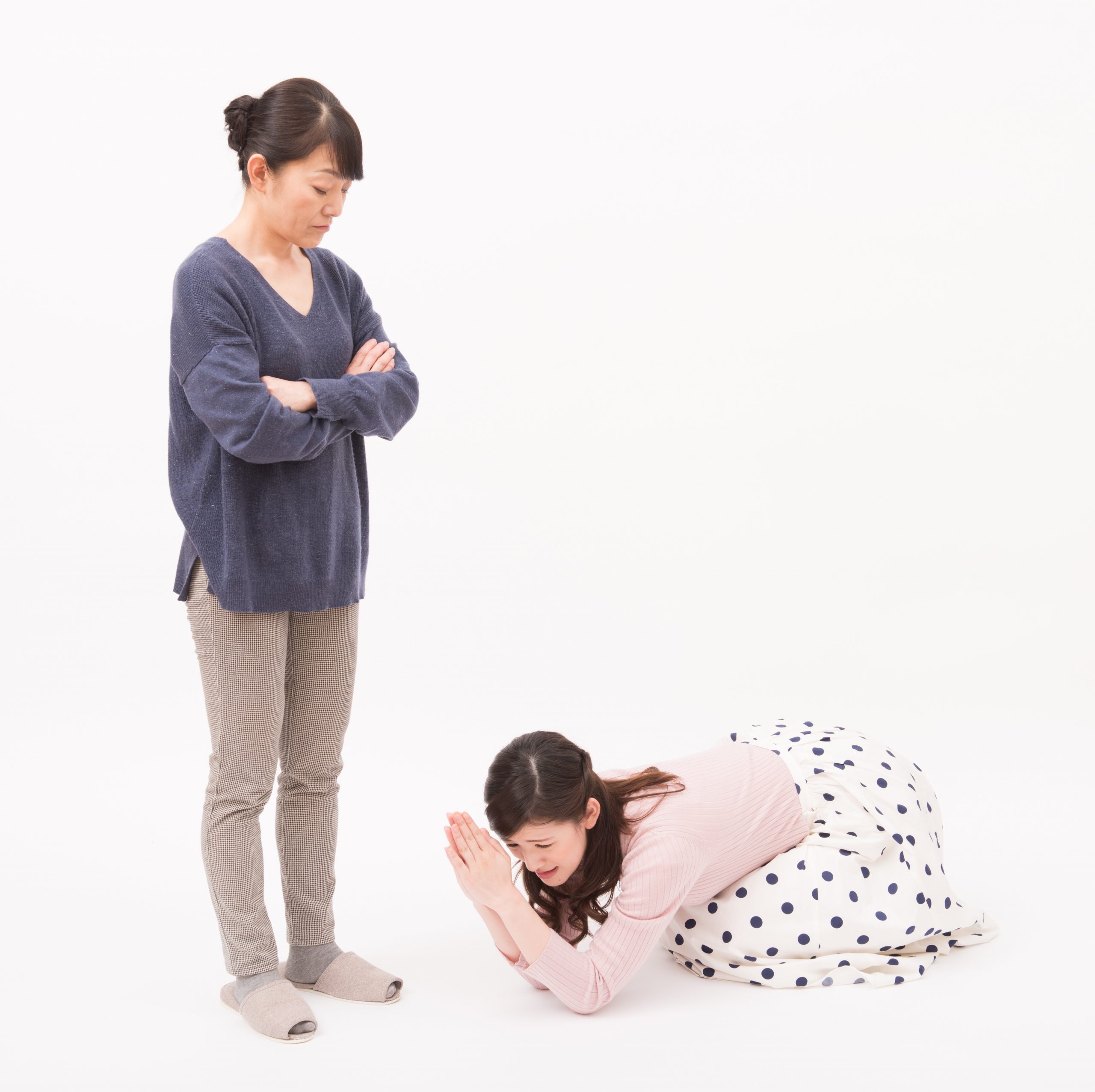 Japanese woman kneeling and apologizing to another woman