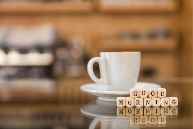 Free photo good morning wooden blocks with cup of coffee on glass counter